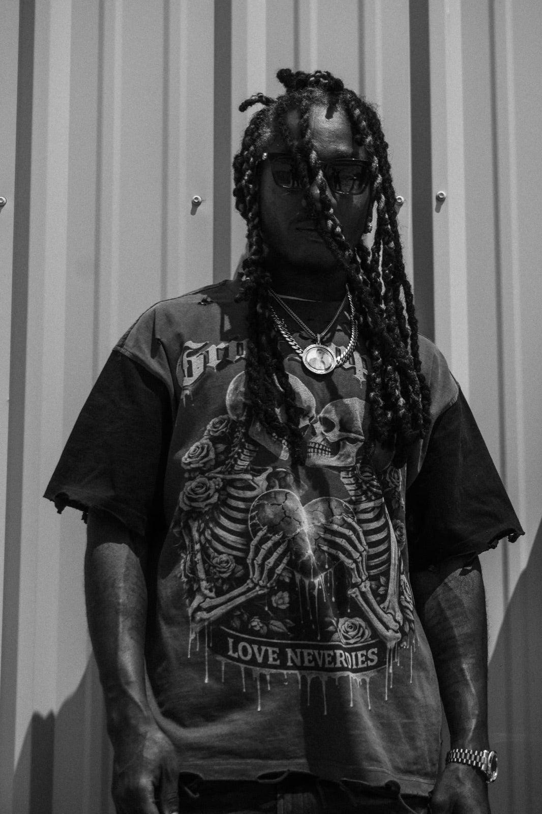 Love Never Dies tee — portrait against corrugated steel